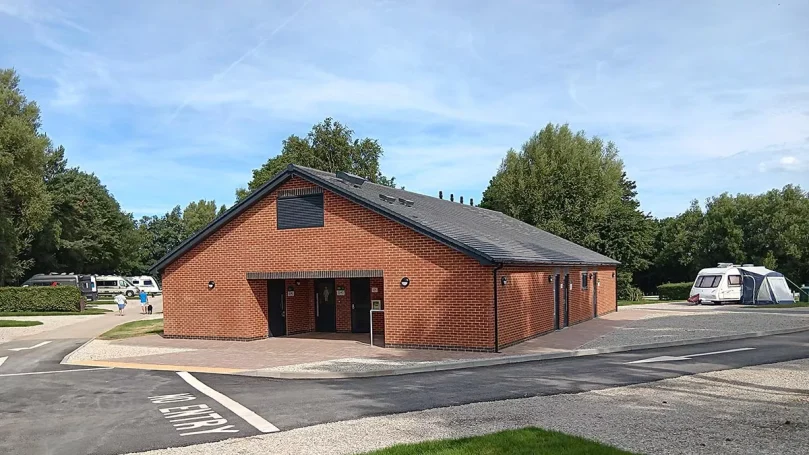 Modern brick built building surrounded by caravans and greenery