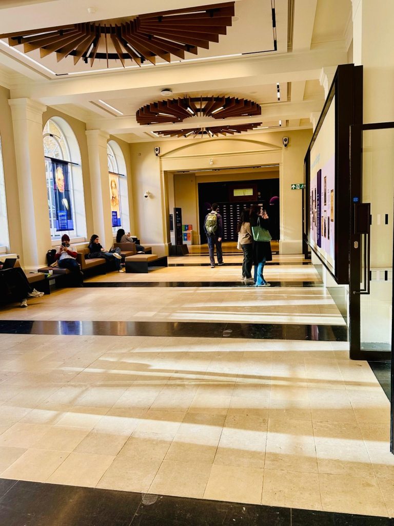 University College London - internal corridor Internal view of long corridor within historical building with people sitting on chairs by the windows