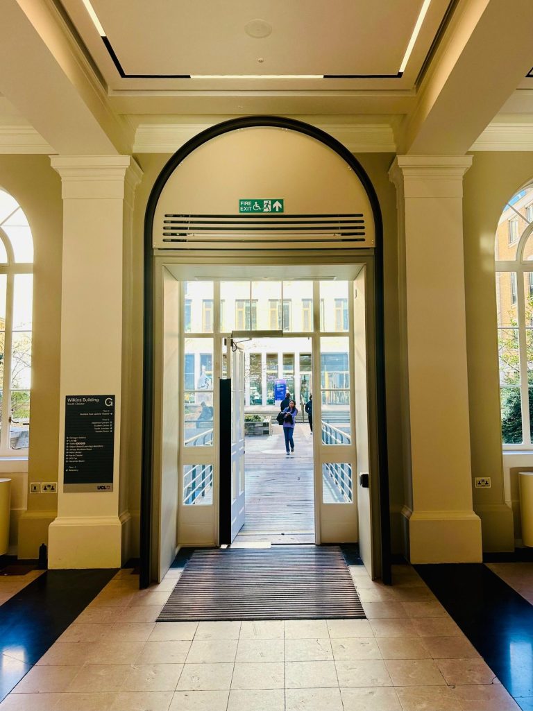University College London View of arched exit door within historical building and people in the external courtyard
