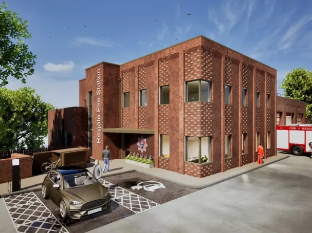 Modern brick building with large windows, parked car, and emergency vehicle outside.